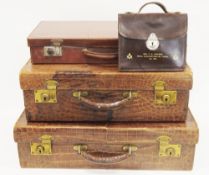 Pair of early 20th century crocodile skin suitcases opening to a peach satin lined interior, with