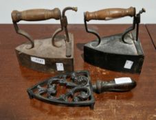 Two Victorian vintage irons with turned wooden handles and a pierced iron trivet (3)