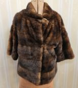 A vintage mink short jacket with roll collar, single button side fastening at the neck, and a