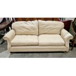 Modern cream upholstered three seater sofa, with scroll arms, on turned tapering front legs with