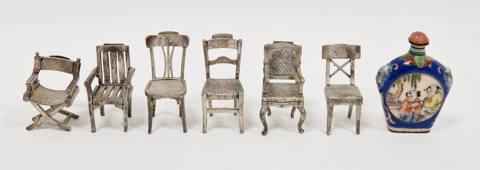 Set of six white metal menu or place name holders, each in the form of a different style of chair,