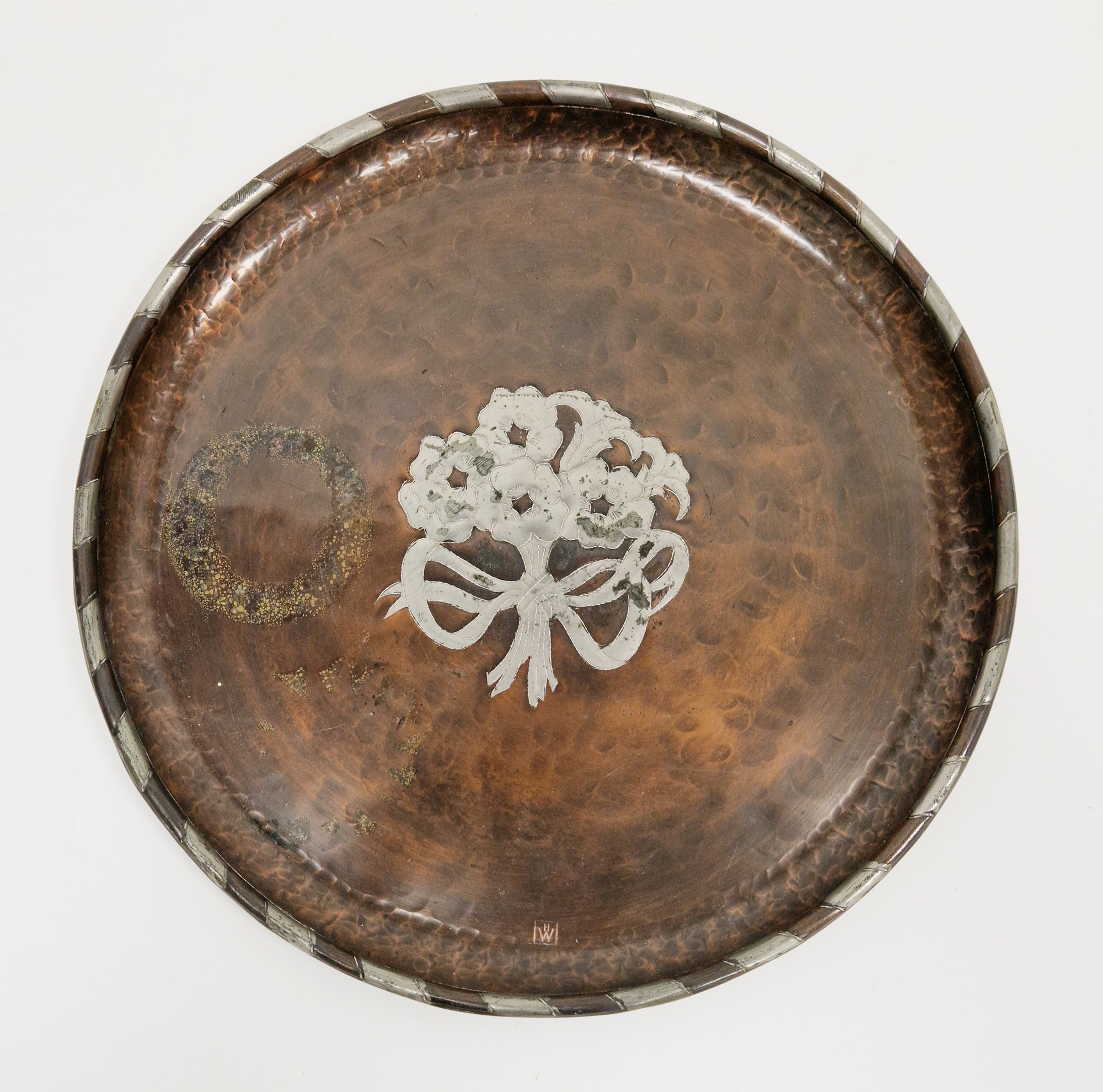 Hugh Wallis (British, 1871-1943), an Arts and Crafts copper and pewter inlaid tray of circular form,