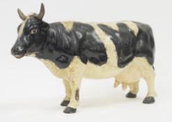 Cast iron painted model of a Friesian cow, 29cm high x 46cm long
