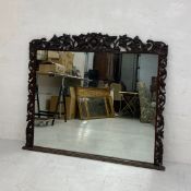 A large 19th century overmantle mirror having a rectangular plate in an ornately carved Baroque