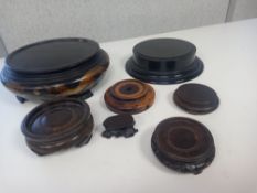 A collection of Chinese and other stands to include carved padouk and a hand decorated lacquered