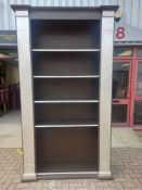 A large Classical style painted bookcase with fluted columns flanking open shelves resting on a