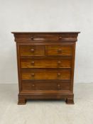 A Victorian style teak chest of drawers with frieze drawer above two short and three long drawers on