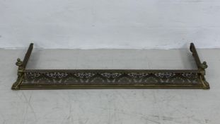 A 19th century brass fire kerb with flaming finials and pierced scrolling foliate detail. H.23 W.146