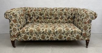 An Edwardian double drop-end sofa in deep buttoned scrolling foliate flowerhead upholstery.