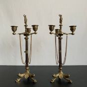 A pair of 19th century French neoclassical style brass candelabras each having a figural finial over