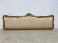 An early 20th century Rococo carved giltwood headboard in damask upholstery. 202x69cm. (mattress