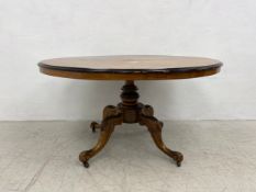A 19th century walnut dining table with central foliate satinwood inlay and tilt top action on