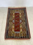 A Turkish rug with central geometric panel on a burgundy ground within multiple stylised borders.