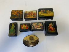 A collection of eight lacquered Russian papier mache dressing table boxes with hand painted