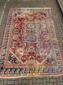 A hand knotted Heriz carpet with flowerhead medallions on a burgundy ground contained within