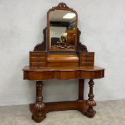 A Victorian mahogany duchess dressing table having a carved superstructure with swing mirror and