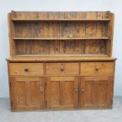 A 19th century pine kitchen dresser with upper plate rack above three frieze drawers and cupboard