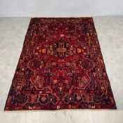 A Persian hand knotted Nahavand carpet with allover geometric polychrome designs over a box red
