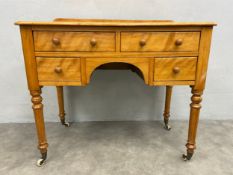 A mid century satin birch kneehole writing or dressing table with an arrangement of drawers on