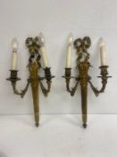 A pair of French 19th century gilt bronze wall sconces each with ribbon cresting over a flame finial