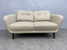 A contemporary retro styled small two-seater 'Arlo' sofa with cream calico upholstery raised on