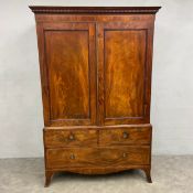 A Georgian mahogany linen press in three parts with dentil moulded cornice over a pair of figured