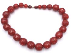 Halskette mit gr. Kugeln in Bernsteinart, wohl Kunststoff, Steine im Verlauf, ca. L-65cm, gr. Stein