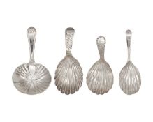 A collection of four George III silver caddy spoons with scalloped bowls.