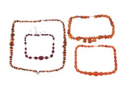 A collection of amber necklaces and a red bead necklace, comprising a graduated faceted oval bead ne