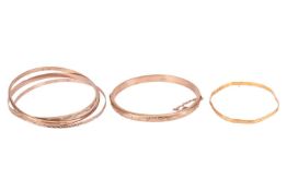 A collection of five bangles; to include a 22ct gold closed bangle with engraved patterns to the ext