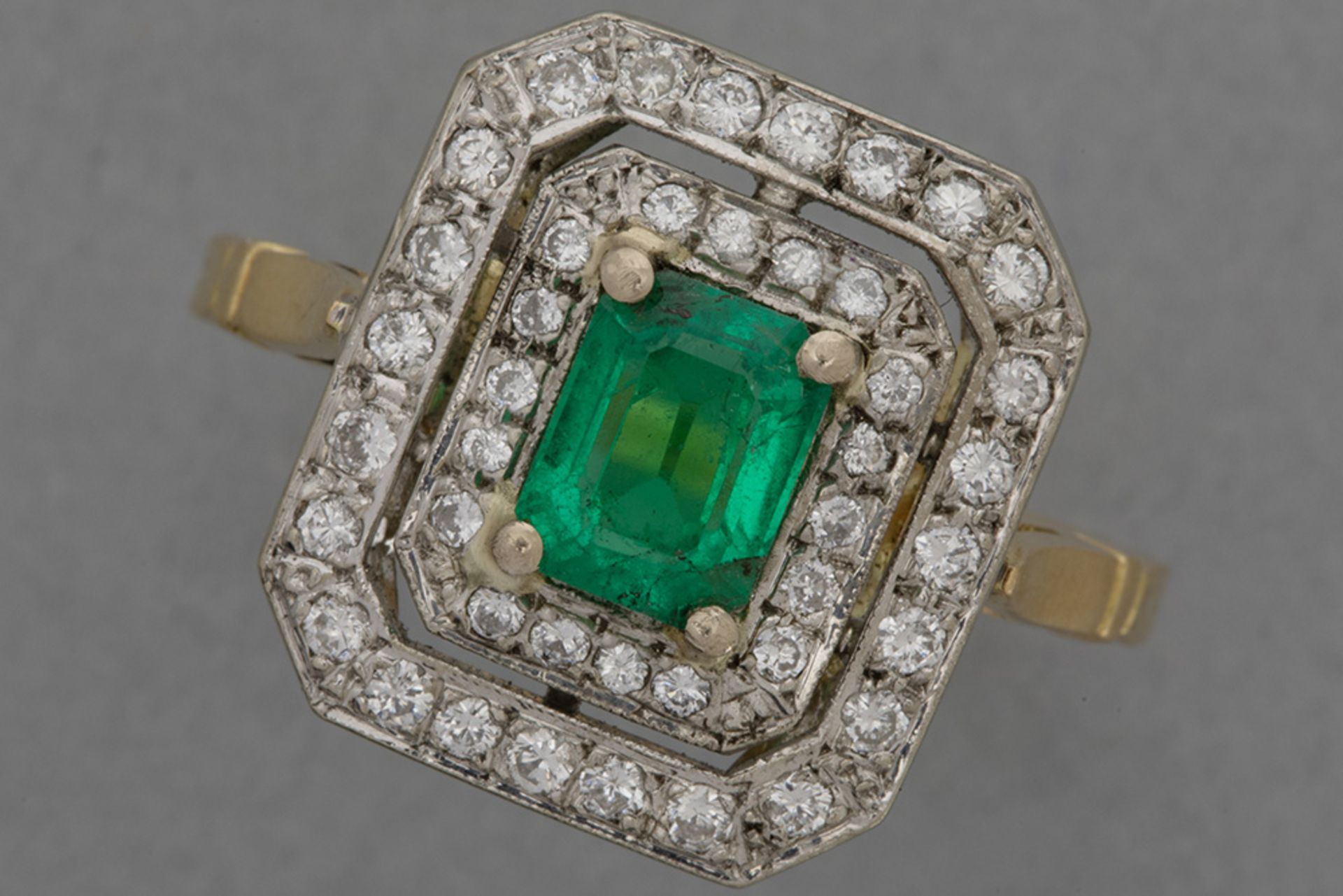 Art Deco style ring in grey gold (18 carat) with a ca 1 carat Colombian emerald surrounded by ca 0,7