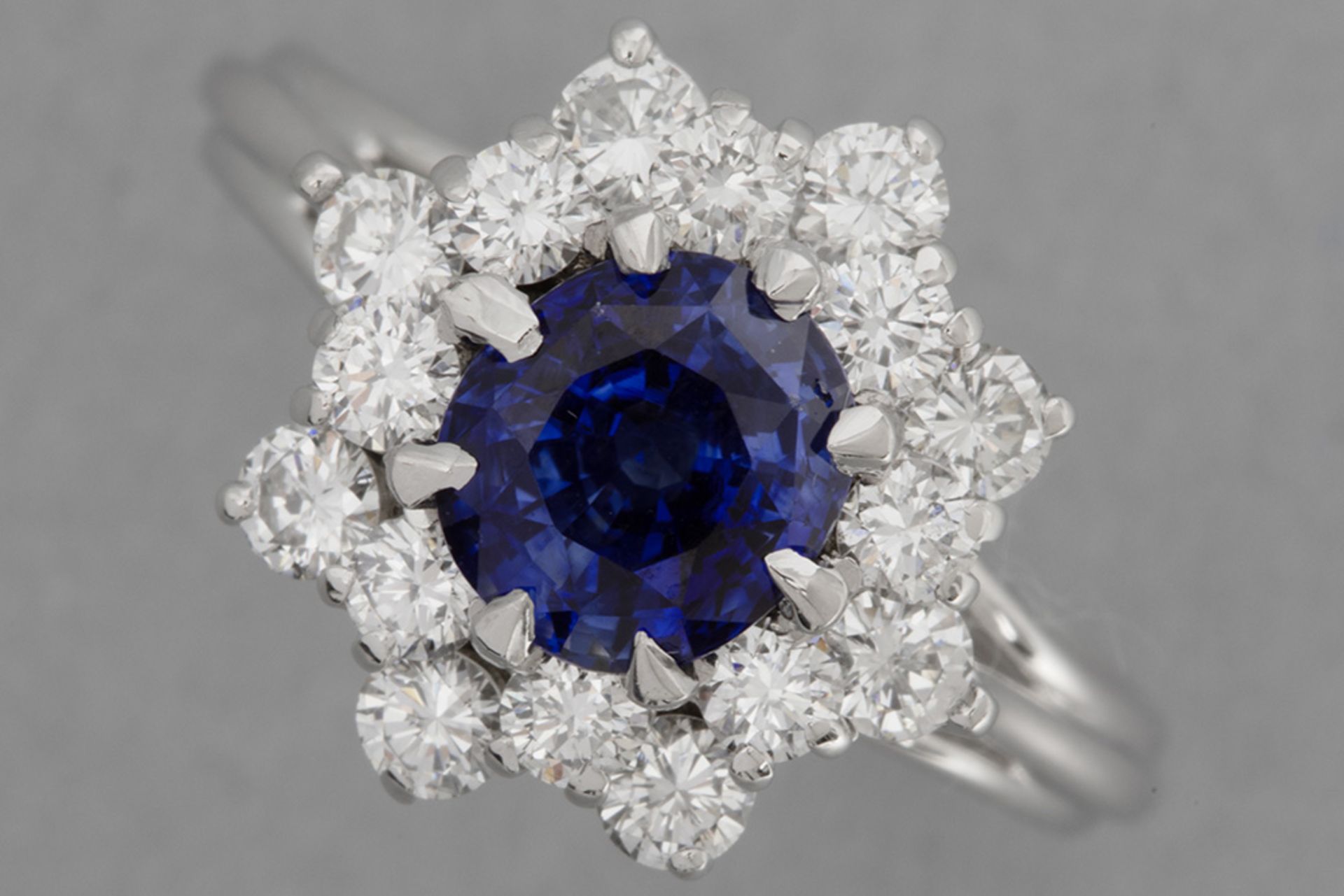 cluster ring in white gold (18 carat) with a ca 1,50 carat Ceylan sapphire surrounded by ca 0,90 car