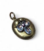 A Victorian yellow metal mourning locket, the obverse set with three oval white stones and a round