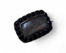 An early 19th century yellow metal mourning brooch, the lock of hair with in a border of faceted