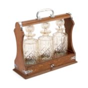 A SILVER-PLATE MOUNTED OAK THREE-BOTTLE TANTALUS