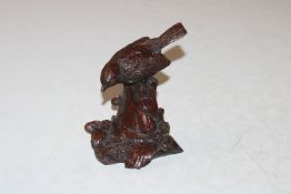 A cast metal model of a bird perched on a flowerpo