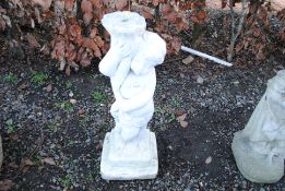 A painted concrete statue in the form of a cherub