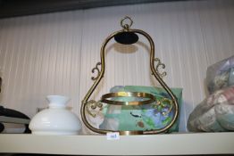 A brass hanging light fitting with glass shade