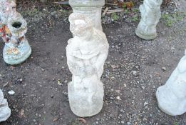 A concrete statue of a seated maiden holding a bir