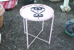 A pink circular metal garden side table and a wall