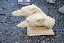 A painted concrete statue of two greyhound heads
