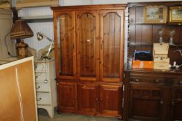 A pine display cabinet raised on cupboard base