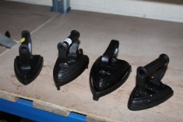 Four various flat irons, two with trivets