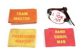 Four various railway armbands, one enamelled badge with leather strap named to 