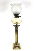 A 19th Century Corinthian column brass oil lamp with ornate brass shade and glass reservoir
