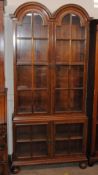 An early 20th Century walnut double dome display cabinet, in two sections, the adjustable shelves