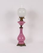 A Victorian pink opaque glass oil lamp, of baluster form raised on gilt metal scroll base complete
