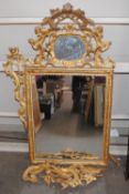 A 18th Century carved gilt wood wall mirror, the foliate scroll pediment with inset small mirror (AF