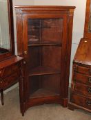 A Continental walnut free standing corner display cabinet, enclosed by a glazed panelled door,