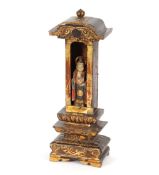 An Eastern gilded and lacquered shrine figure, with haloed saint and attached coin, 32cm high